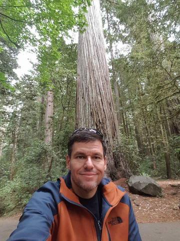 Program presenter Marc DeWerth in front of large tree in a forest.